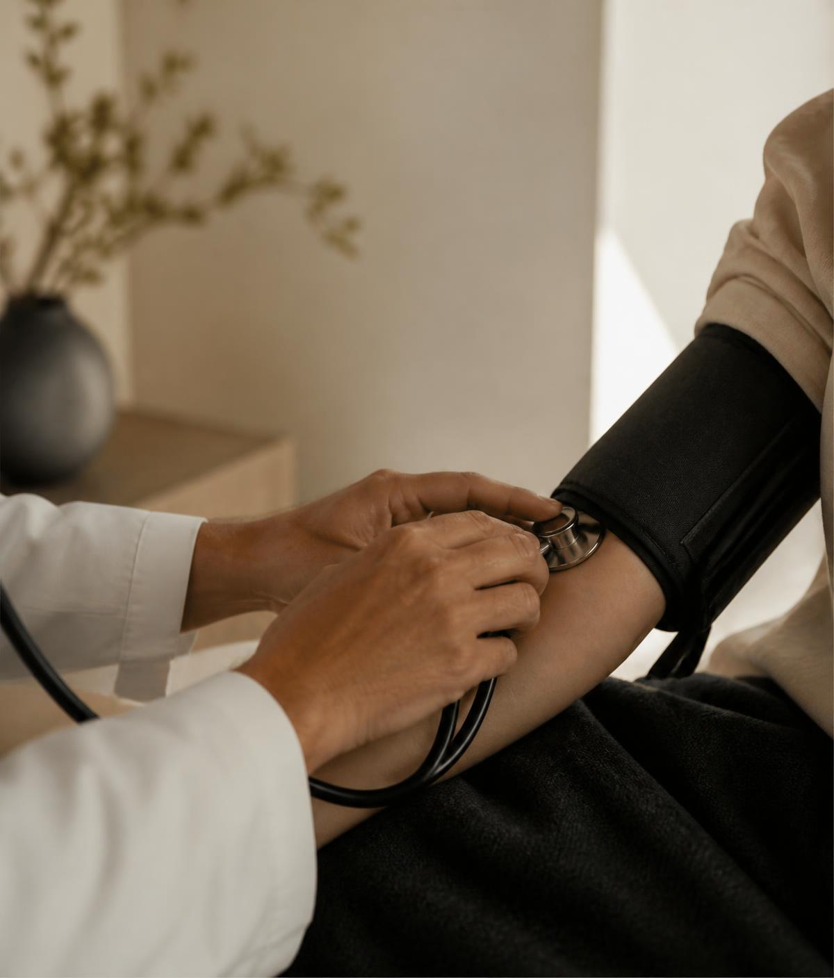 A physician taking a patient's blood pressure in a warm, minimal consultation room